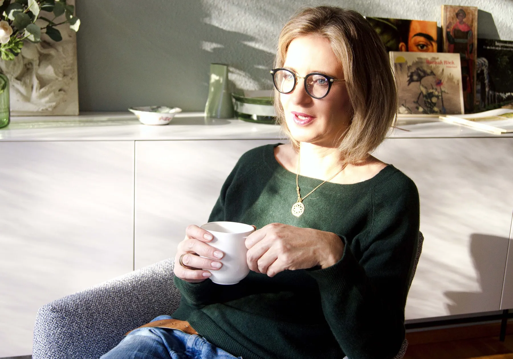 Katrin Funke in ihrer Praxis in Duisburg, am Fenster, mit einer Tasse in der Hand